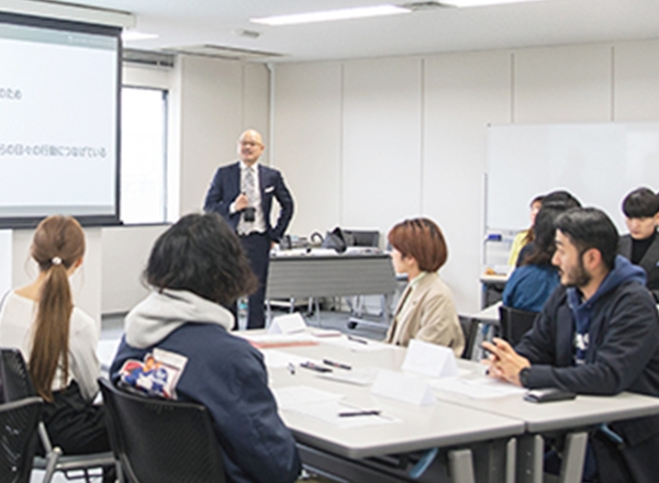 スクリーンの前に座り、講義を受けるスタッフたち