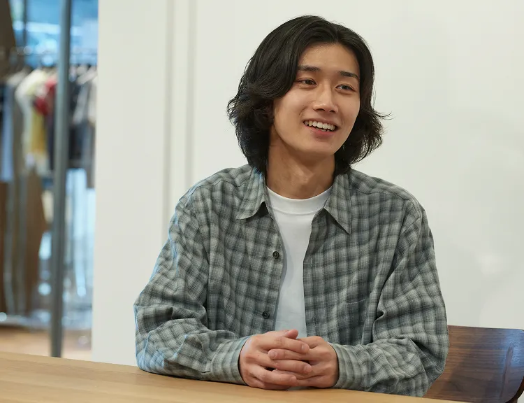 机に手を乗せて、受け答えをしているサクマさん