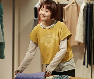 ディスプレイテーブルに置いてあるセーターを畳んでいるササキさん